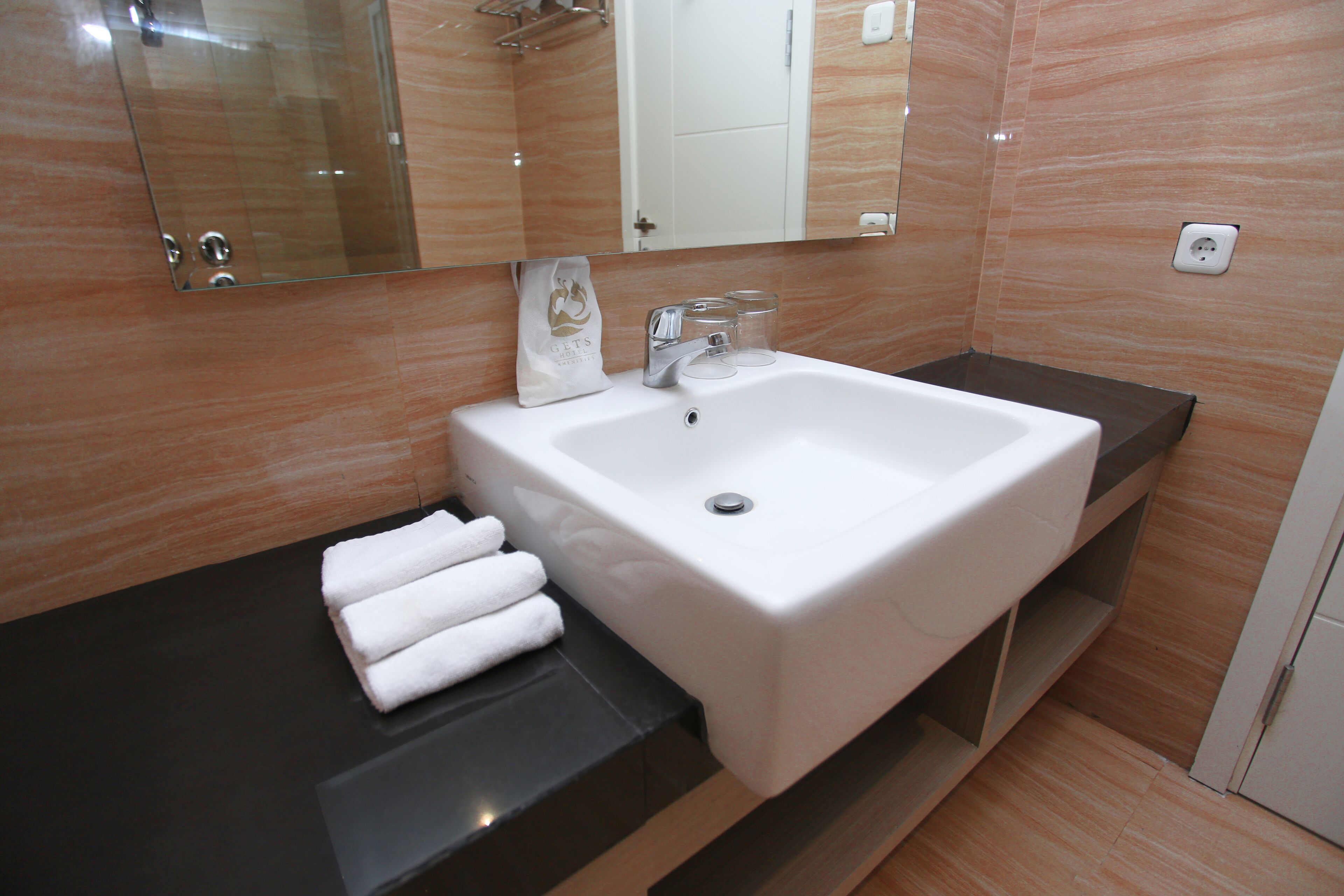 A modern bathroom with a white sink, a mirror, and a towel rack.