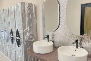 Un baño con dos lavamanos redondos, un espejo y una pared con textura.