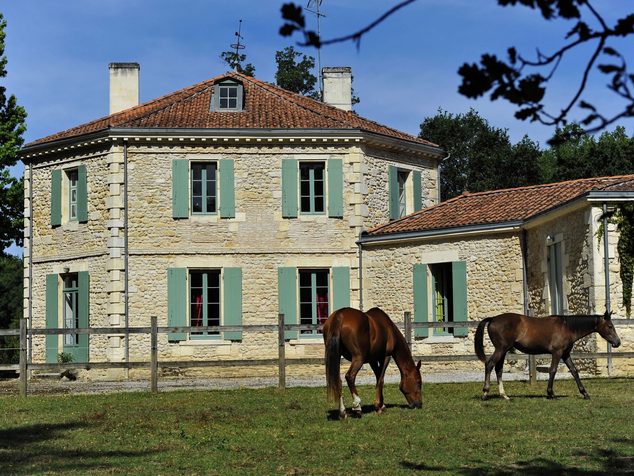 A stone building with green shutters and a red-tiled roof.