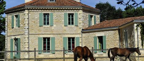 A stone building with green shutters and a red-tiled roof.