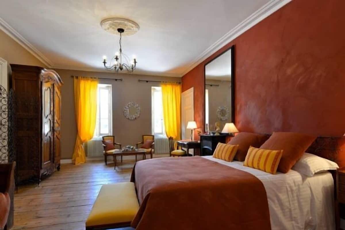 Ein Hotelzimmer mit einem großen Bett, einer Bank, einem Schreibtisch und einem Stuhl.