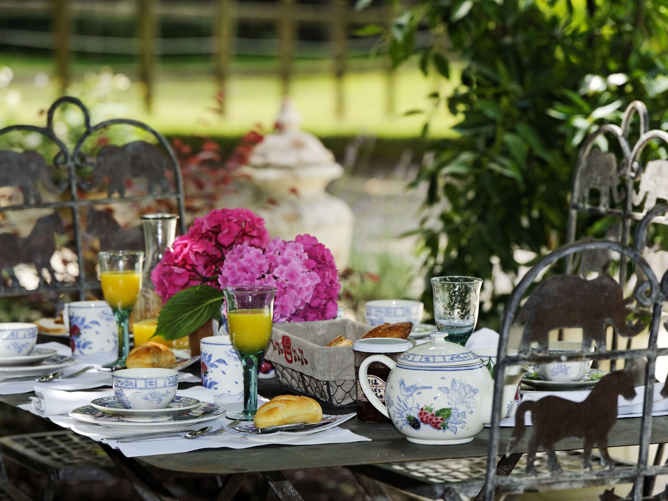 Une table dressée avec divers éléments pour le petit-déjeuner, notamment une théière, des tasses et des viennoiseries.