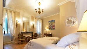 Une chambre avec un grand lit, une cheminée, un bureau et une chaise.