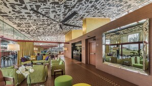 A modern hotel lobby with green seating, a large window, and a patterned ceiling. - Villaverde Hotel & Resort - Wellness Spa & Golf (Fagagna)