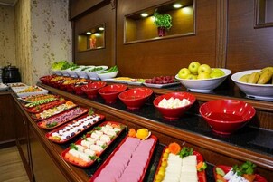 A buffet with various food items and a potted plant on the wall.