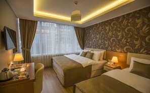 Habitación de hotel con dos camas, un escritorio con lámpara, teléfono y televisor montado en la pared.