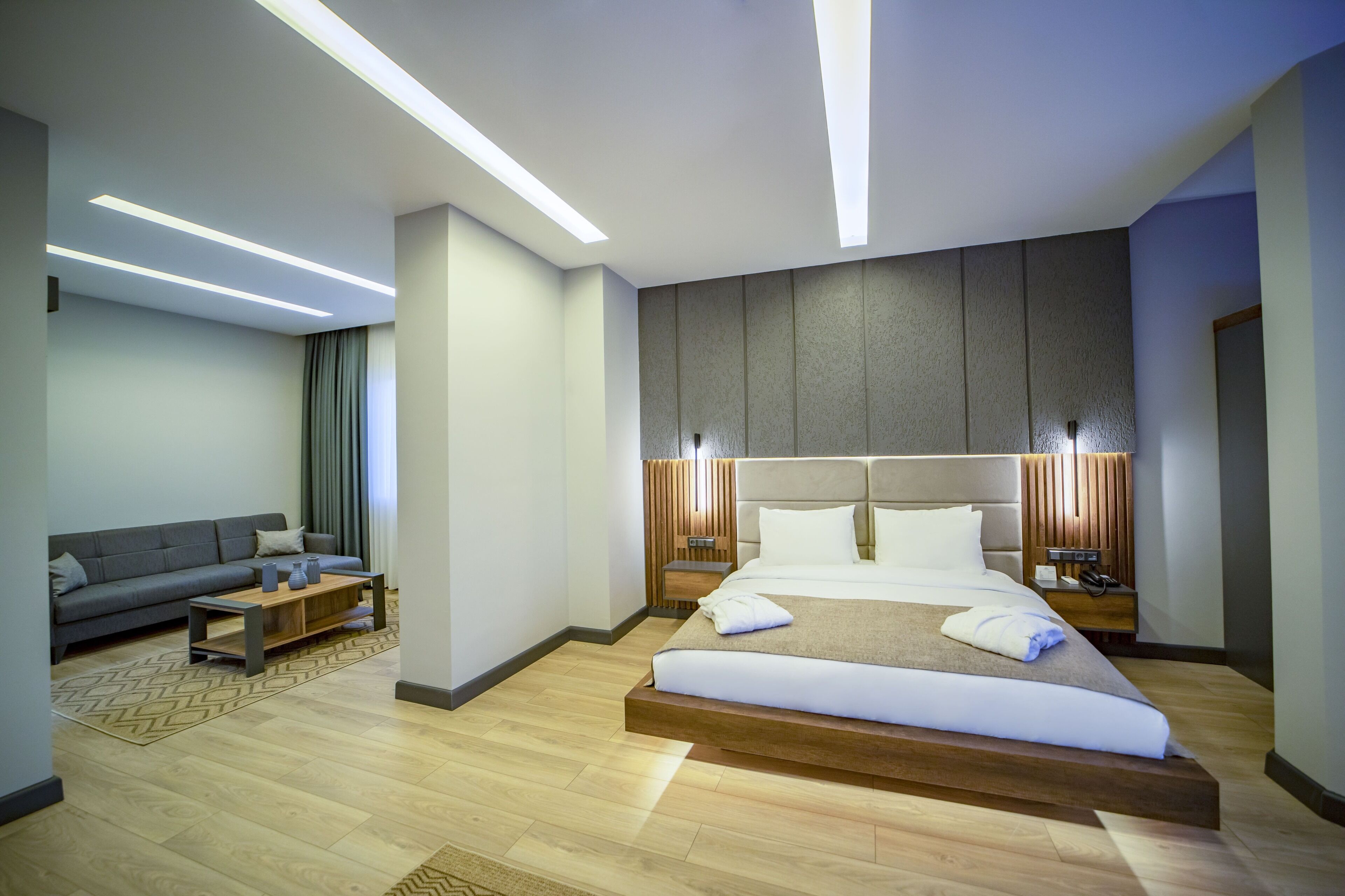 Una habitación de hotel moderna con una cama grande, un sofá, una mesa de centro y una mesita de noche.