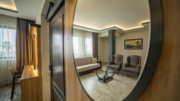 Una habitación de hotel moderna con un escritorio de madera, un sofá, dos sillones y una mesa de centro.