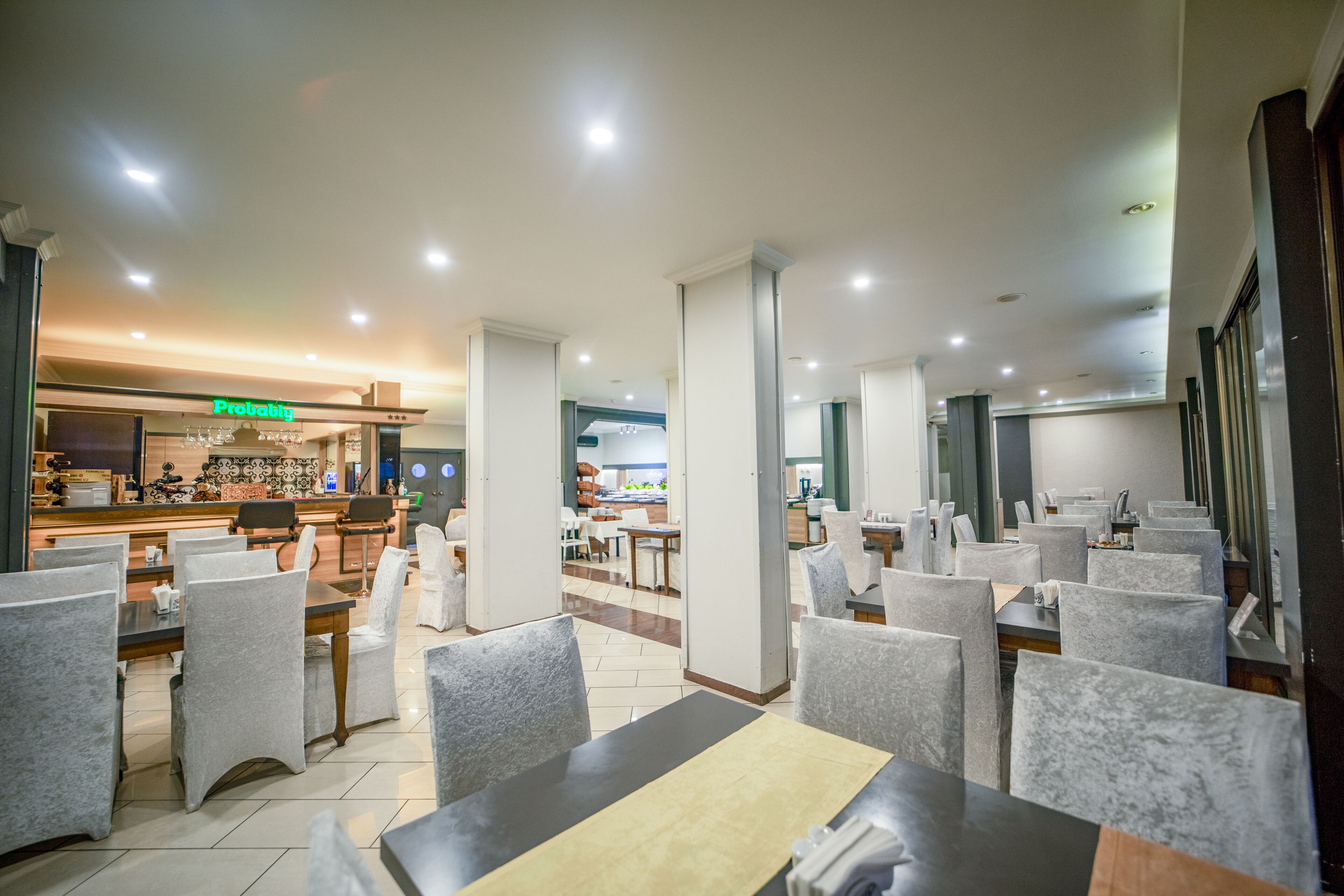 A modern restaurant with a bar area, multiple dining tables, and chairs.