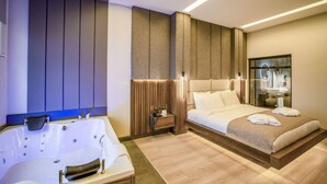 A modern hotel room with a large bed, a separate bathroom with a bathtub, and a small bedside table. - Aksular Hotel (Trabzon)