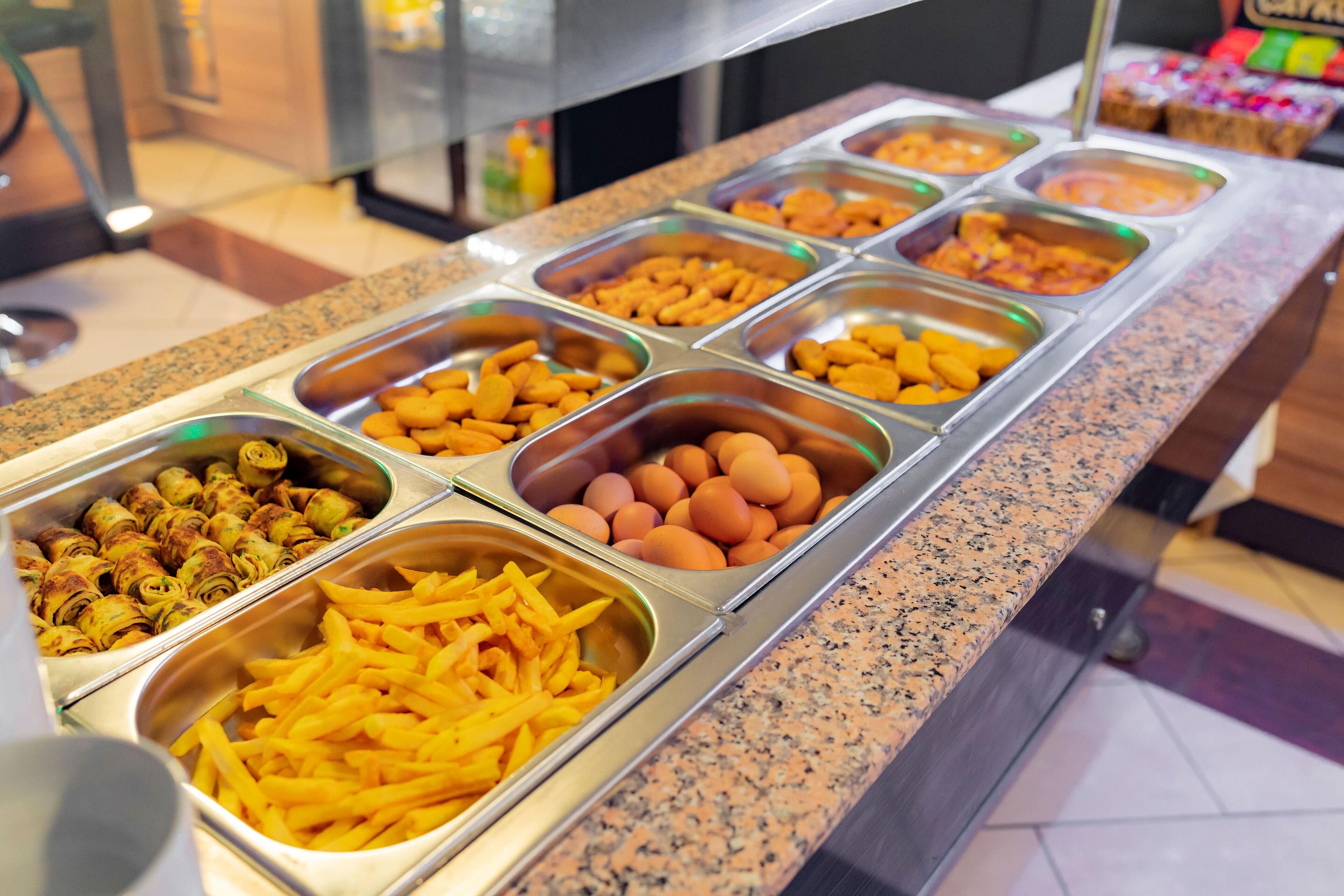 A buffet with various food items including eggs, French fries, and other snacks.