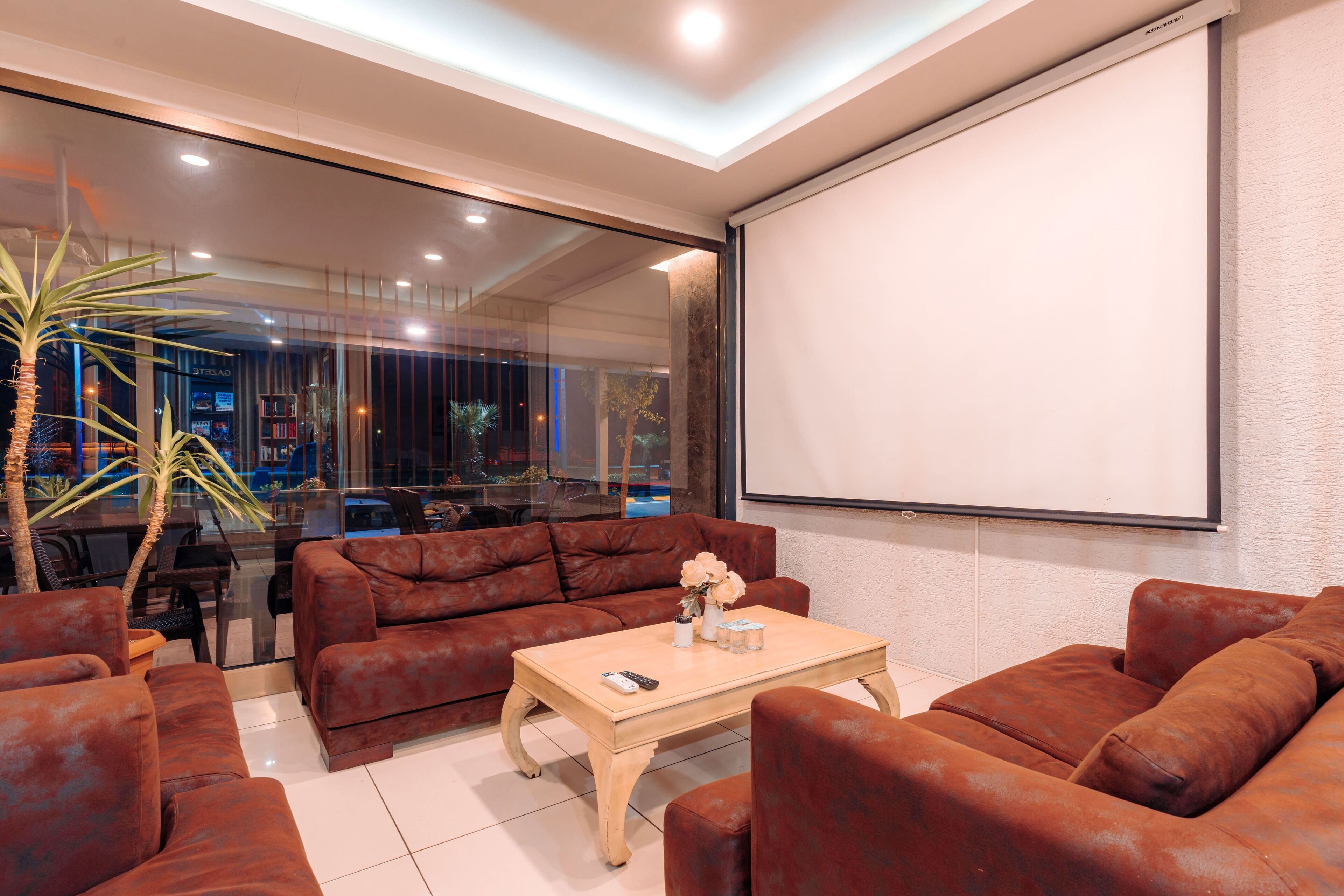 A modern living room with leather sofas, a coffee table, and a large screen.