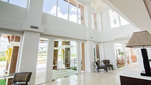A spacious hotel lobby with high ceilings, large windows, and a view of the outdoors. - The Lake Hotel (Khon Kaen)