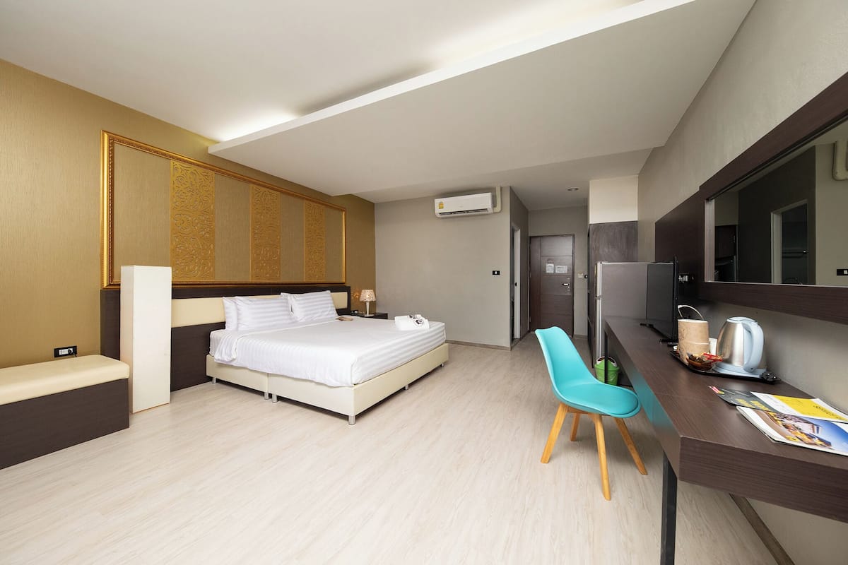 Una habitación de hotel moderna con cama, escritorio, silla, televisión y aire acondicionado.