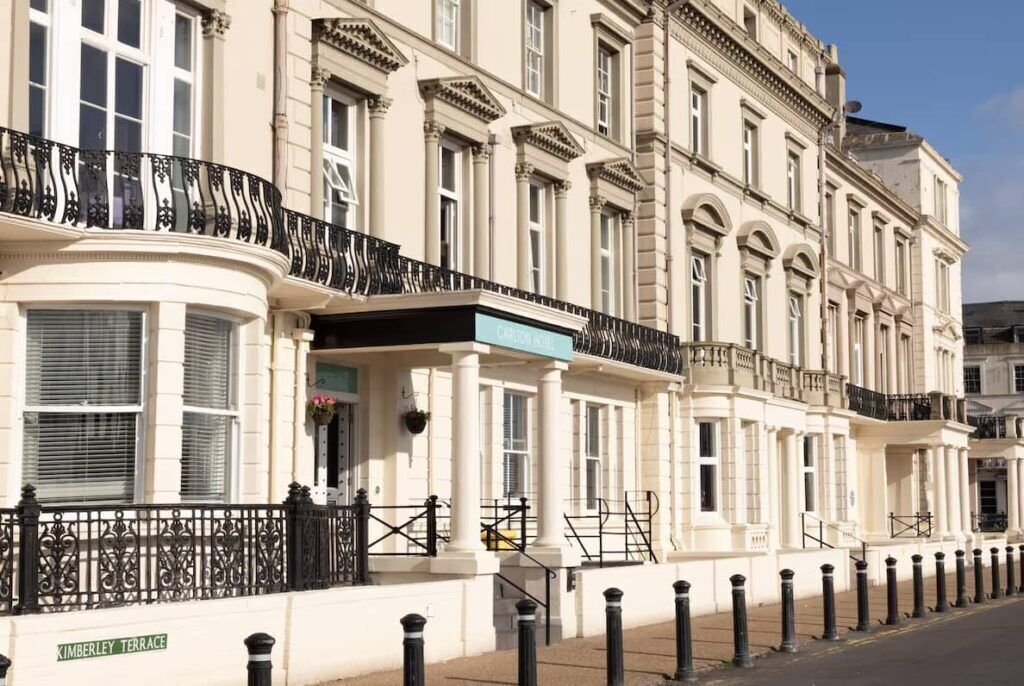 A row of classic white buildings with black iron railings, a sign for 'Charing Cross,' and a 'Kimberley Terrace' sign.