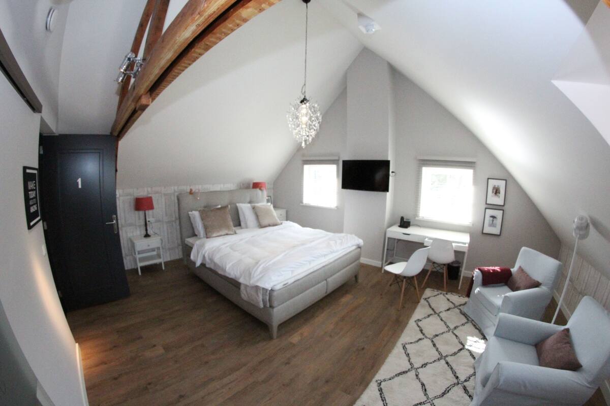 A bedroom with a bed, a desk, a chair, and a TV.