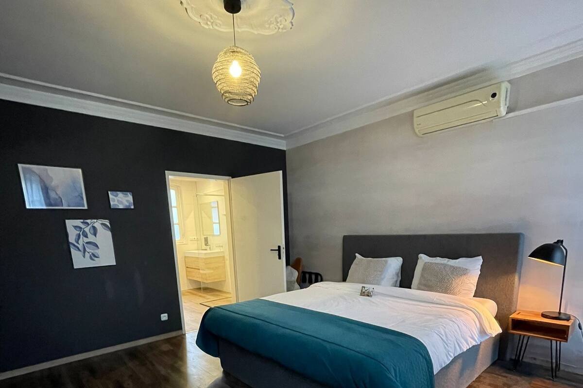 A bedroom with a bed, a nightstand, a lamp, and a ceiling light fixture.