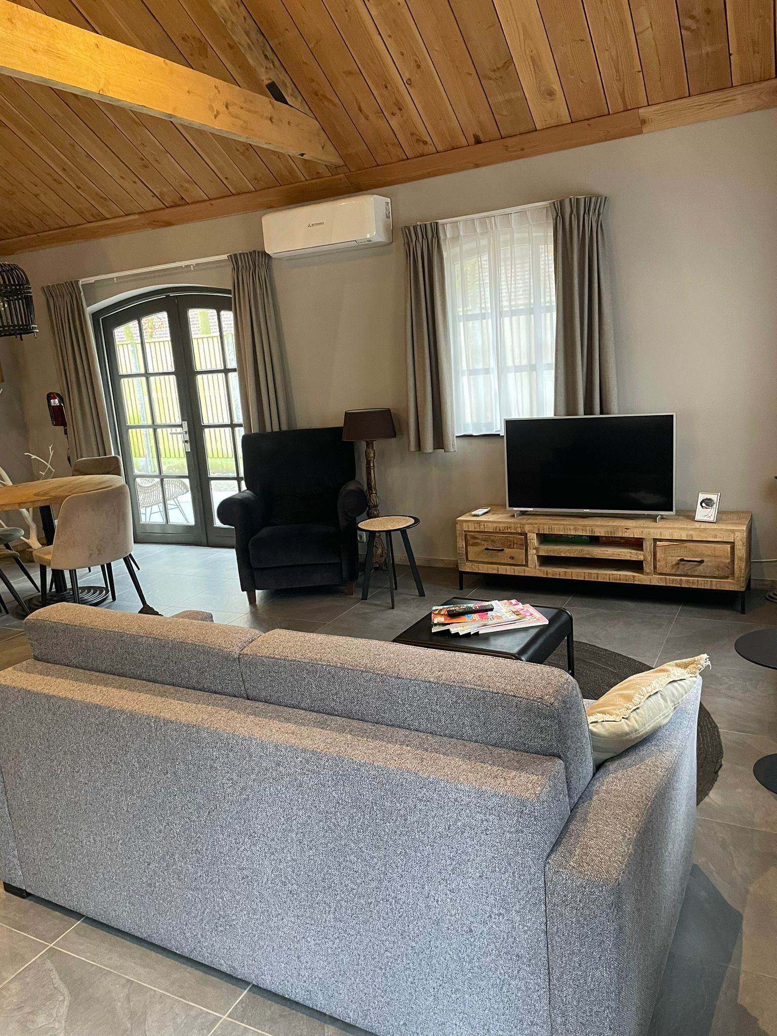 Ein Wohnzimmer mit einer Couch, einem Sessel, einem Fernseher und einem Holzschrank.