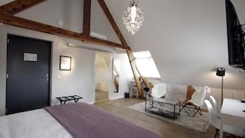 A bedroom with a bed, a desk, a chair, a chandelier, and a staircase.