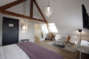 A bedroom with a bed, a desk, a chair, a chandelier, and a staircase. - Hotel In de Witte Dame (Grubbenvorst)