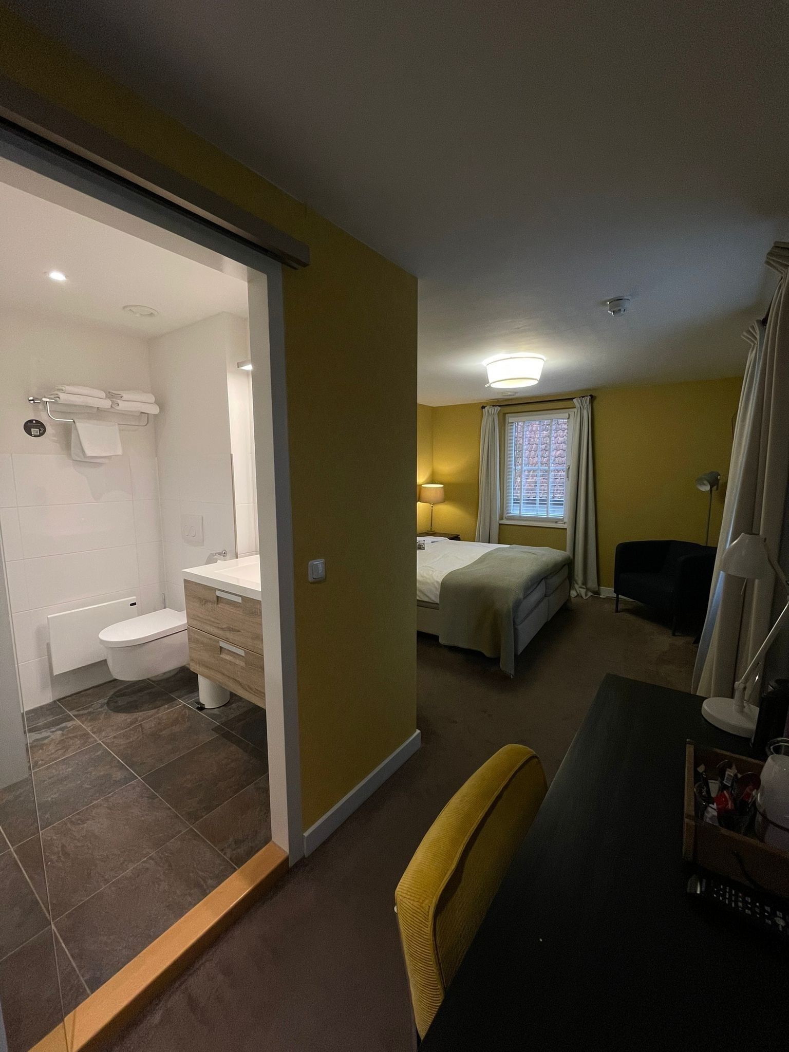 Een hotelkamer met een badkamer, een bed, een bureau en een stoel.