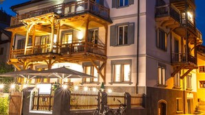 Un edificio de varios pisos con balcones, un espacio exterior cubierto para sentarse y bicicletas estacionadas afuera.