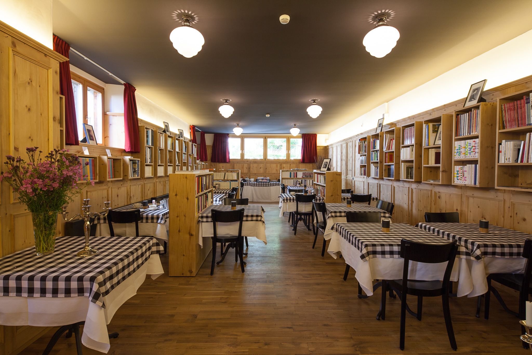 A library with wooden bookshelves, checkered tables, and chairs.