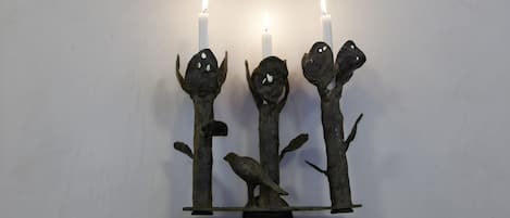 Un candelabro de pared con tres velas y una escultura de pájaro.