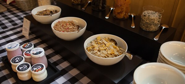 A breakfast buffet with various cereals and yogurt cups.