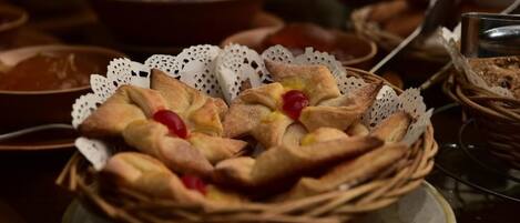 A basket of bread rolls with a cherry on top, placed on a table with other food items.
