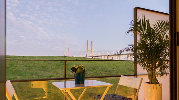 A balcony with two chairs, a table, and a potted plant. - Oriente Rio Apartments by APT IIN - Parque das Nações (Lisbon)