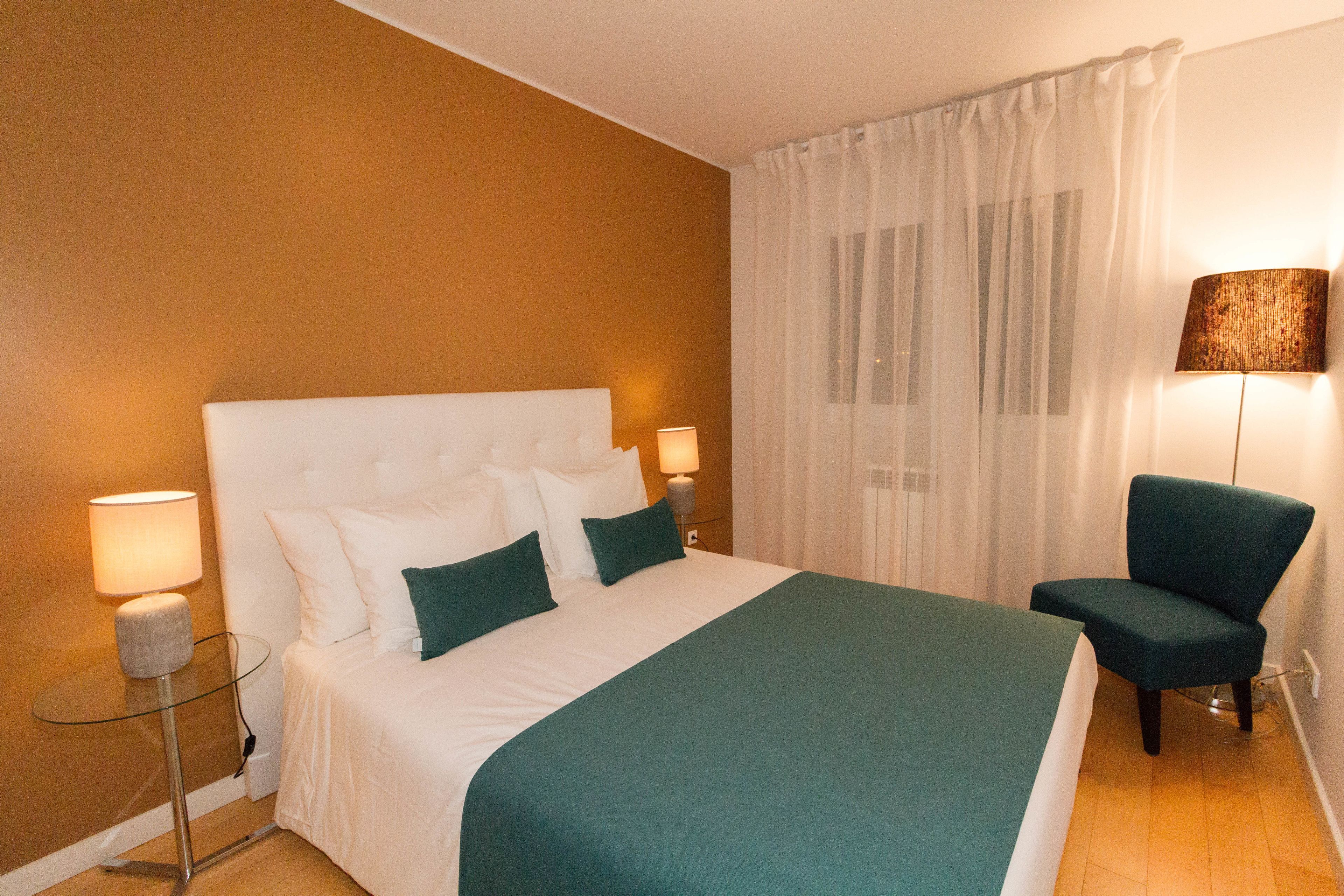 Ein Hotelzimmer mit einem großen Bett, einem Sessel und zwei Nachttischlampen.