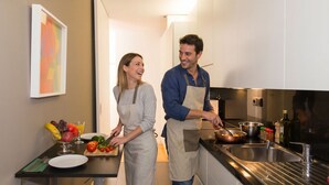 A modern kitchen with a stainless steel sink, a cutting board with vegetables, and a fruit bowl. - Oriente Rio Apartments by APT IIN - Parque das Nações (Lisbon)