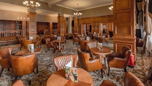 A spacious lobby with leather seating, wooden paneling, and a patterned carpet.