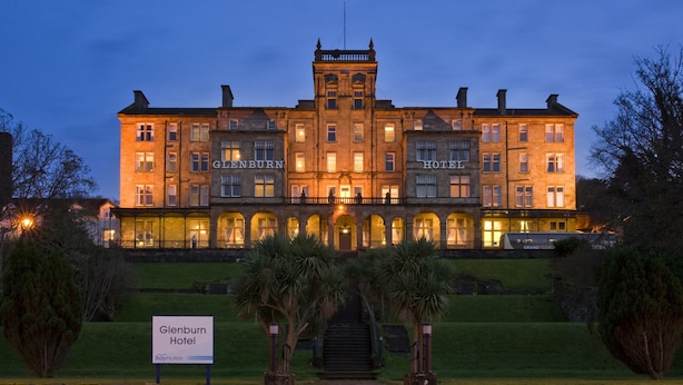 A large, historic hotel building with multiple stories, a prominent entrance, and a well-maintained lawn.