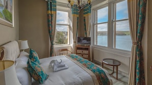 A hotel room with a bed, a TV, a chair, and a view of a lake.