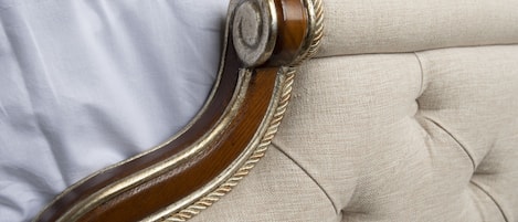 A close-up of a tufted headboard with a wooden frame and rope detailing.