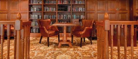 Een bibliotheek met boekenplanken, een tafel en leren stoelen.
