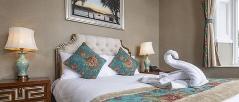 A hotel room with a large bed, two bedside tables, a framed picture on the wall, and a window with curtains.