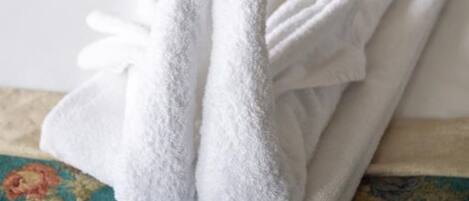 A neatly folded white towel on a bed with floral-patterned bedding and matching pillows.