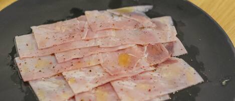 A black plate with sliced meat on a wooden table.