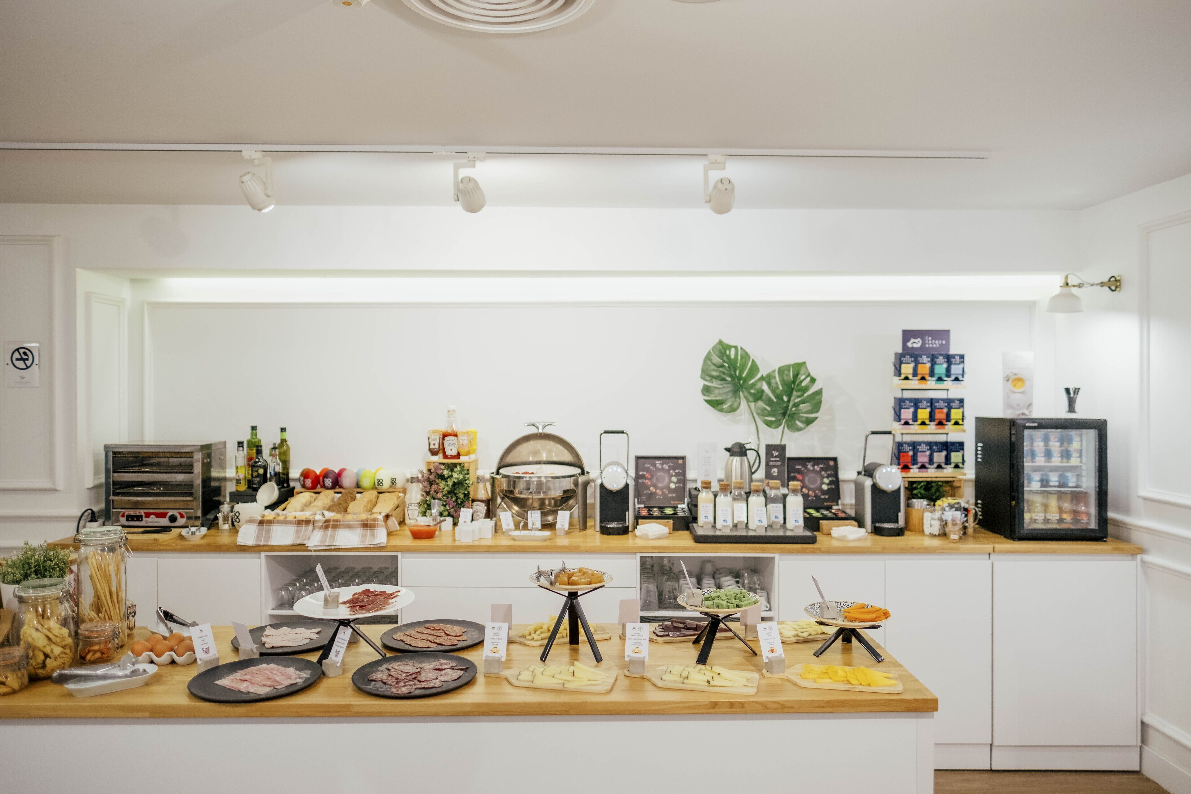 A breakfast buffet with various food options, a coffee machine, and a refrigerator.