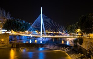 A nighttime view of a modern bridge with a central tower, surrounded by water and trees. - Hotel Cetina Murcia (Murcia)