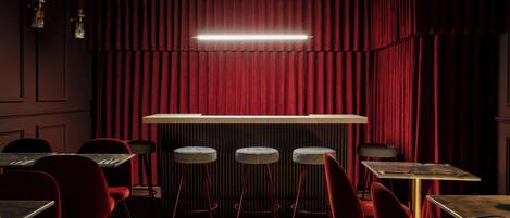 A bar area with red curtains, bar stools, and tables.