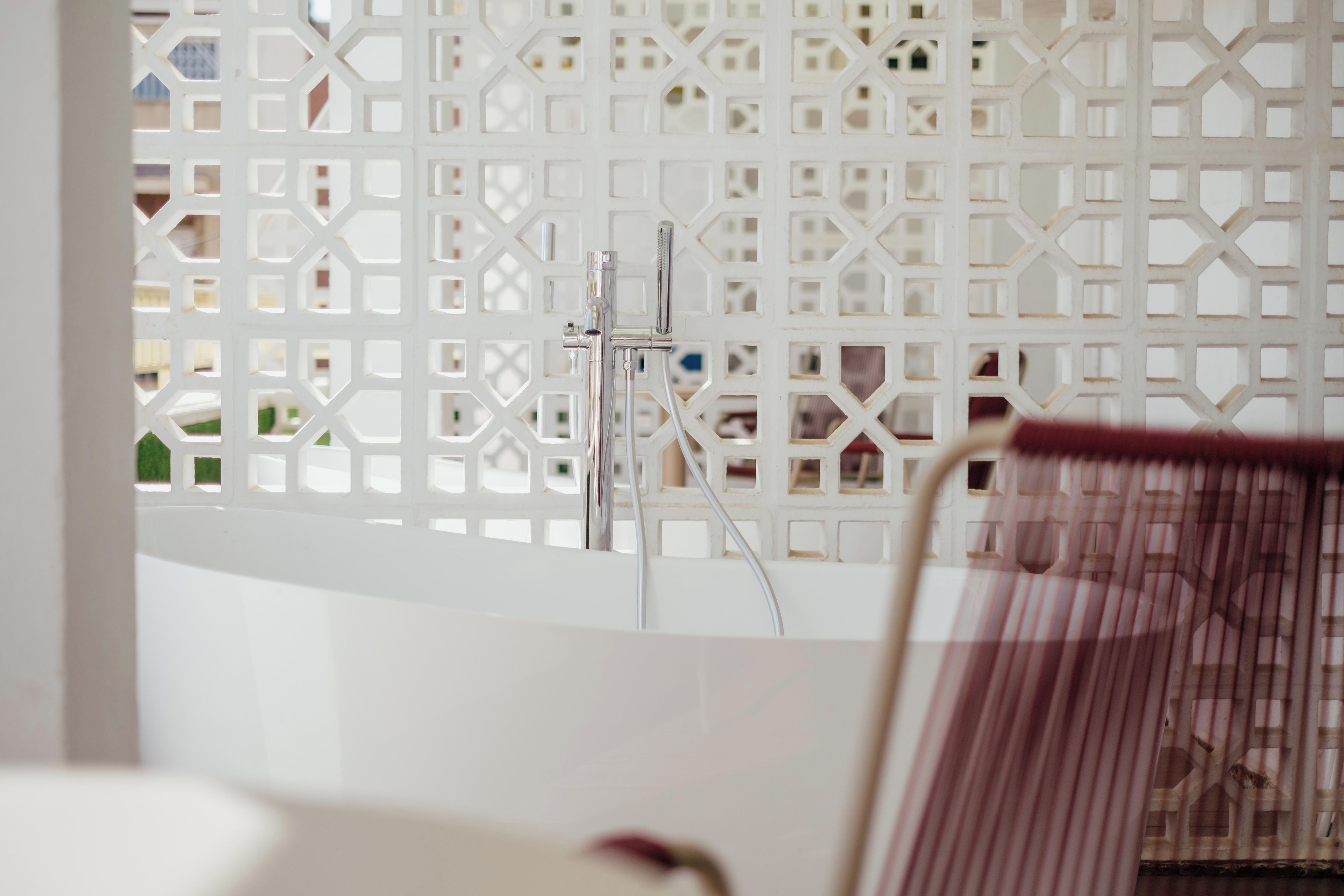A bathroom with a white shower enclosure, a visible showerhead, and a partial view of a chair.