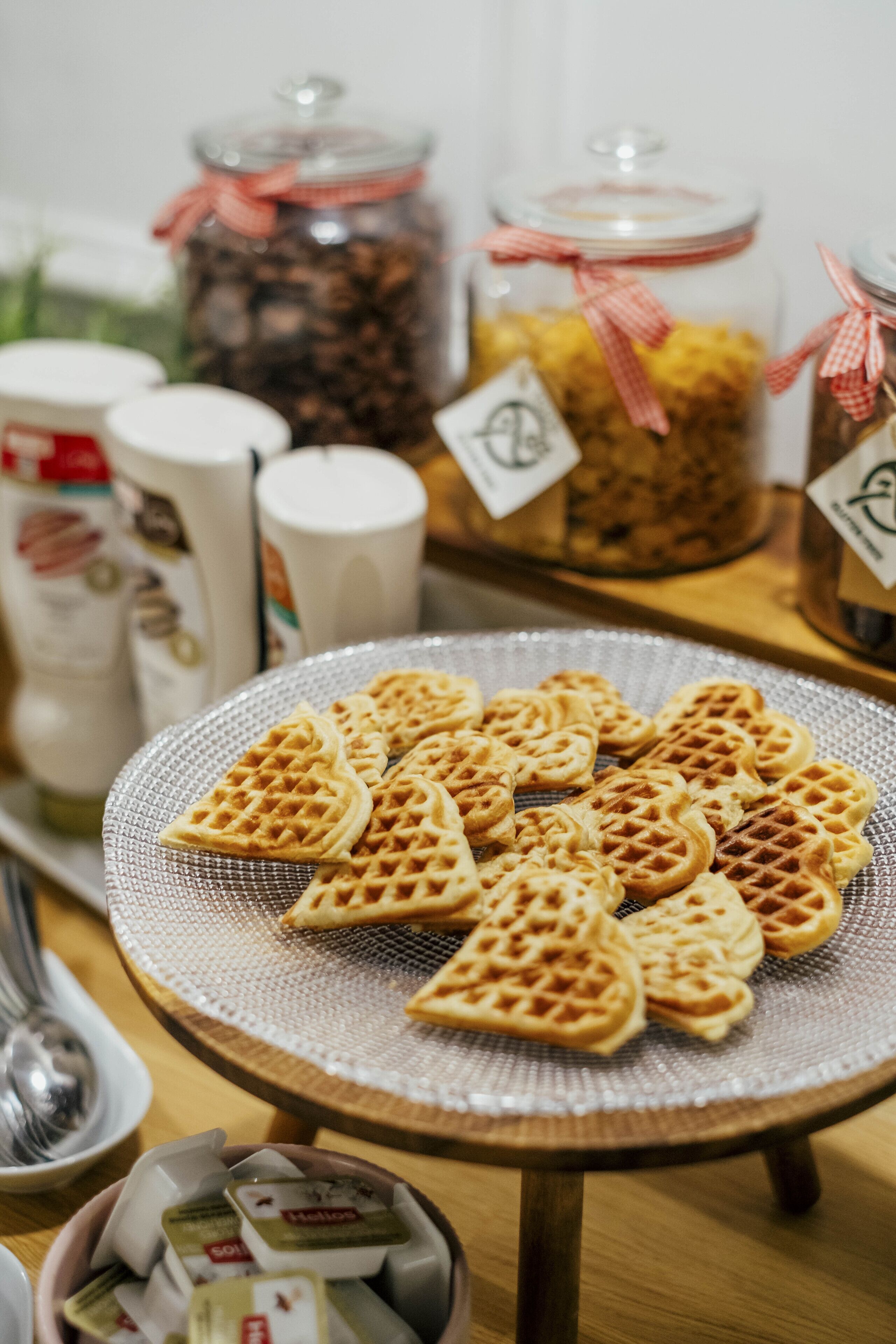 A table with heart-shaped waffles and jars of condiments.