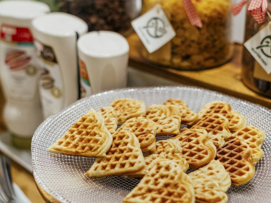 A table with heart-shaped waffles and jars of condiments.