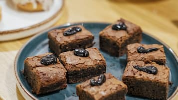 Un plato de brownies con salsa de chocolate sobre un plato azul.