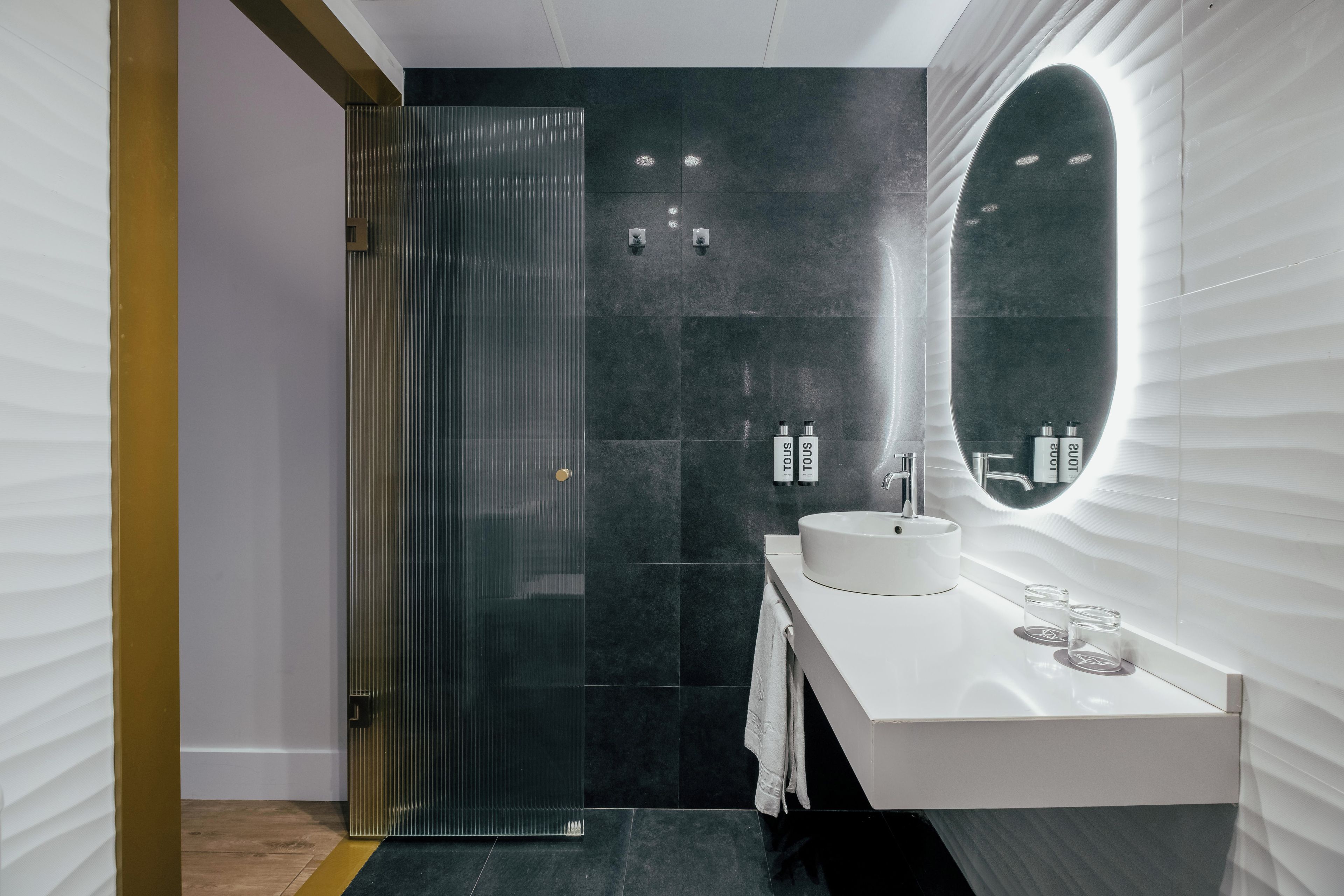 A modern bathroom with a white sink, a large mirror, and a glass shower enclosure.