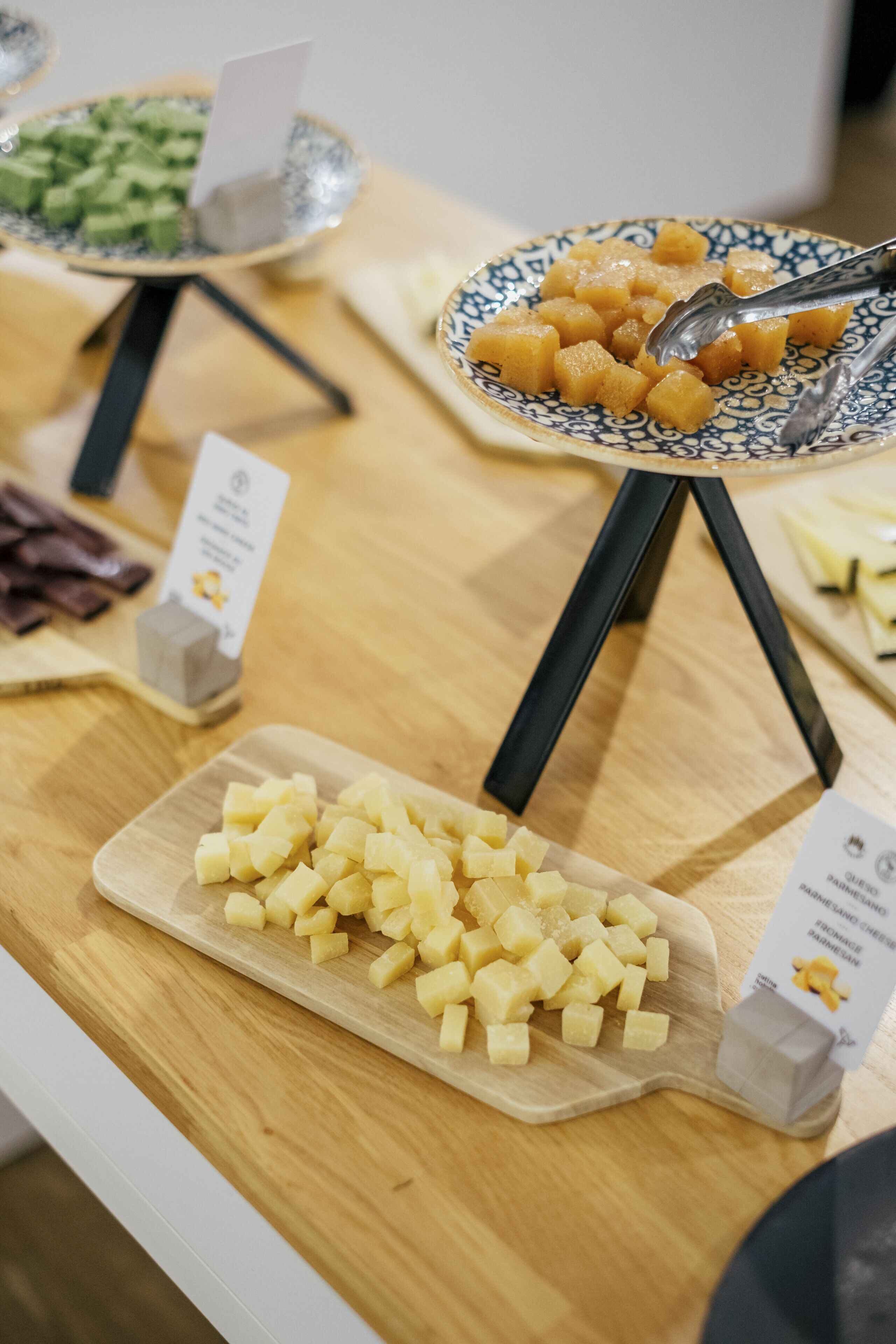 Een buffettafel met diverse etenswaren, zoals blokjes kaas, blokjes fruit en een schaal gemengde groenten.